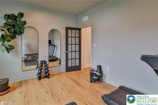workout room featuring baseboards, visible vents, and wood finished floors