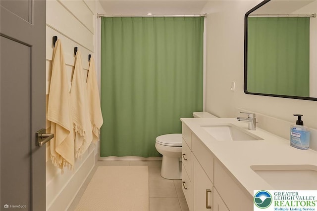 bathroom with a sink, tile patterned flooring, toilet, and double vanity