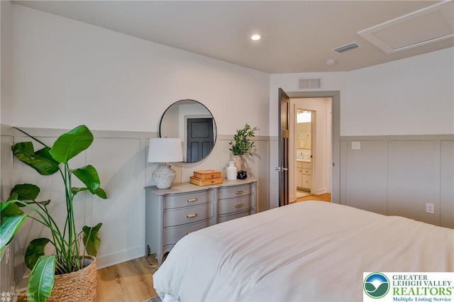 bedroom featuring recessed lighting, attic access, light wood finished floors, wainscoting, and visible vents