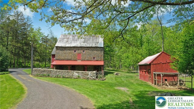 8043 Richlandtown Rd, East Rockhill Twp, PA 18951 - view of front of property with stone siding, a front yard, metal roof, and an outbuilding