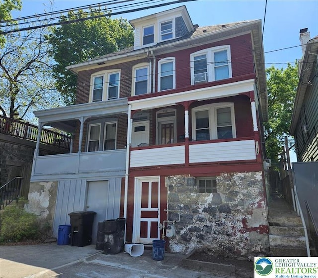 view of front of property with stone siding and a balcony