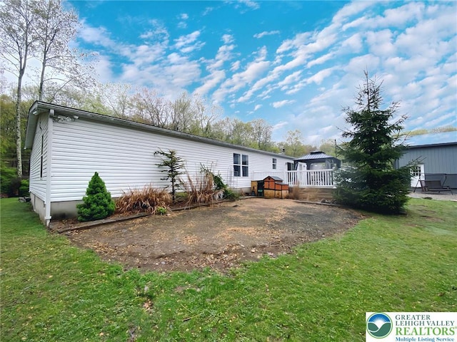 rear view of house featuring a gazebo and a lawn
