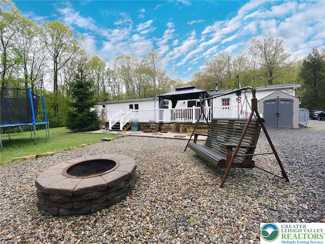 back of house with a trampoline, a fire pit, a gazebo, a storage shed, and a deck