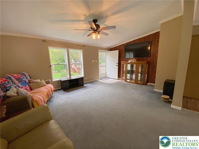 living room with a ceiling fan, crown molding, lofted ceiling, wood walls, and carpet floors