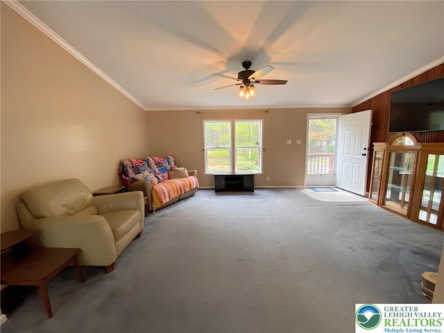 living area with crown molding, ceiling fan, carpet, baseboards, and wood walls