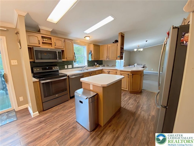 kitchen featuring appliances with stainless steel finishes, crown molding, a peninsula, light countertops, and wood finished floors