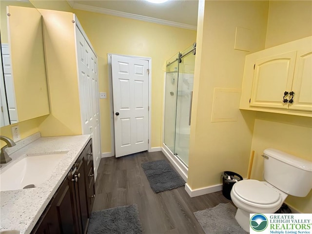 full bathroom featuring wood finished floors, a stall shower, ornamental molding, vanity, and toilet
