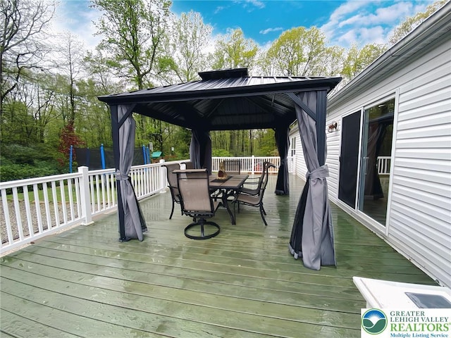wooden terrace with outdoor dining area and a gazebo