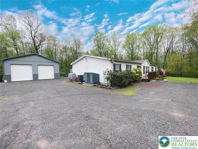 view of side of home with a garage, an outbuilding, central AC, and a wooden deck