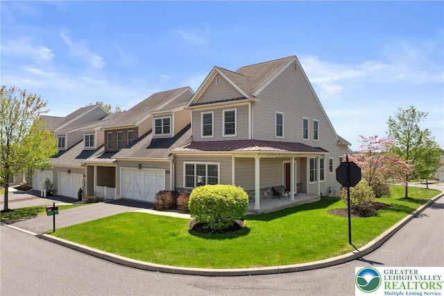 view of front facade featuring driveway, a front lawn, a garage, metal roof, and a standing seam roof