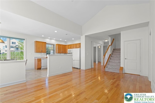 unfurnished living room with light wood finished floors, stairway, baseboards, lofted ceiling, and recessed lighting
