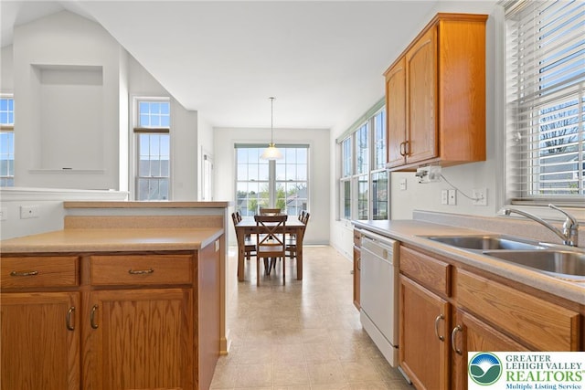 kitchen with white dishwasher, a sink, light countertops, brown cabinetry, and hanging light fixtures