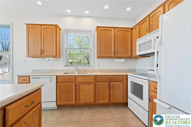 kitchen with white appliances, a sink, light countertops, recessed lighting, and brown cabinetry