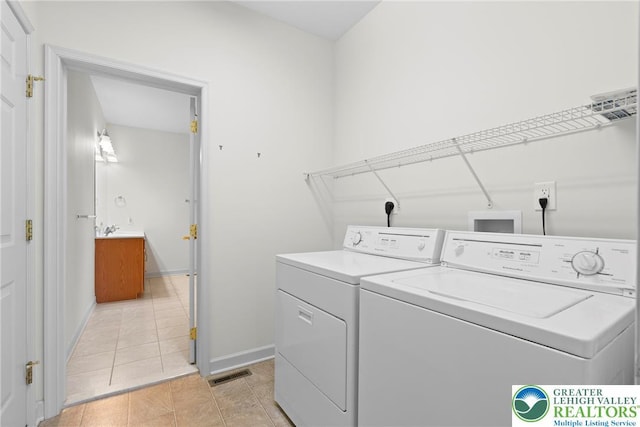 laundry area featuring washer and dryer, light tile patterned flooring, and baseboards