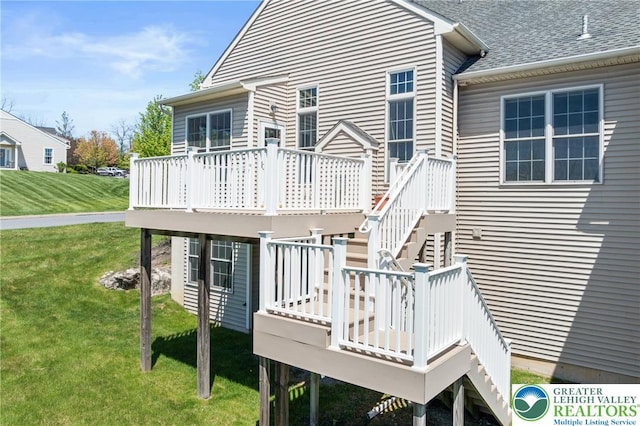 rear view of property featuring a deck, stairway, and a lawn