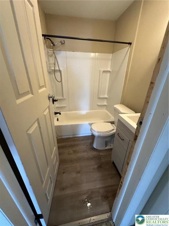 bathroom with wood finished floors, toilet, vanity, and  shower combination