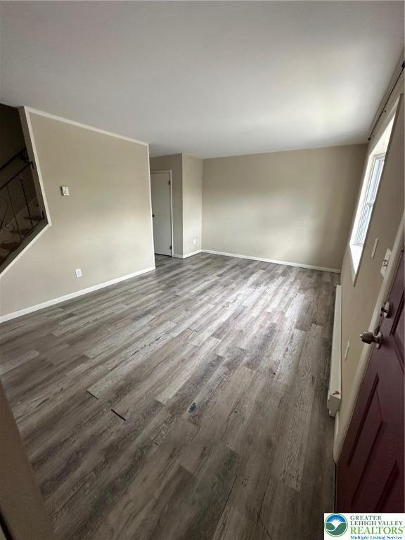 unfurnished room with wood finished floors, baseboards, and stairs