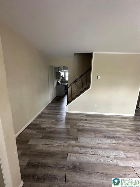 unfurnished living room with wood finished floors, stairs, and baseboards