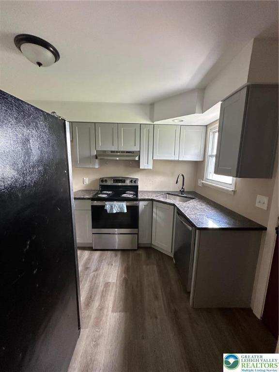 kitchen featuring stainless steel appliances, under cabinet range hood, gray cabinets, and dark wood finished floors