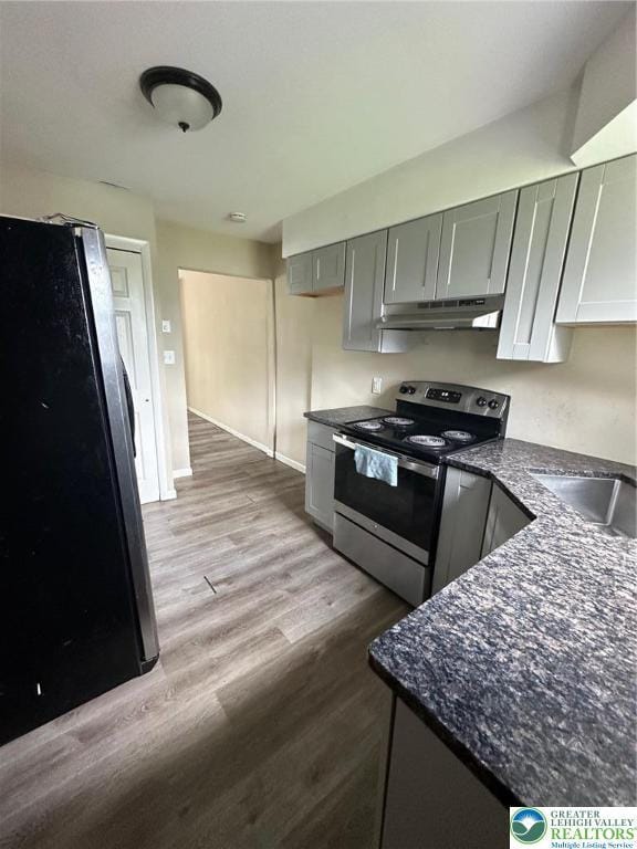 kitchen with stainless steel range with electric stovetop, freestanding refrigerator, gray cabinetry, under cabinet range hood, and wood finished floors