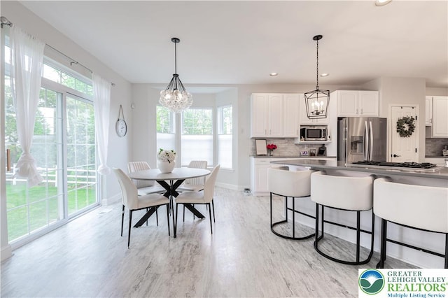 dining area with a chandelier, light wood-style floors, baseboards, and recessed lighting