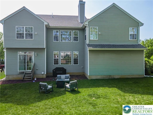back of property with entry steps, a chimney, and a lawn