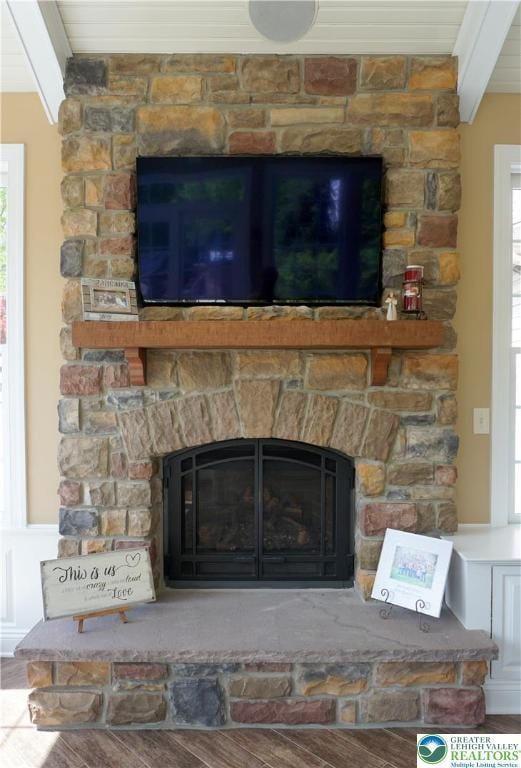 detailed view of a fireplace, beam ceiling, and wood finished floors