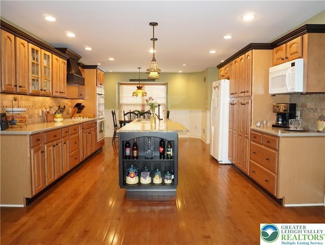 kitchen featuring white appliances, a kitchen island, glass insert cabinets, wainscoting, and dark wood-style flooring