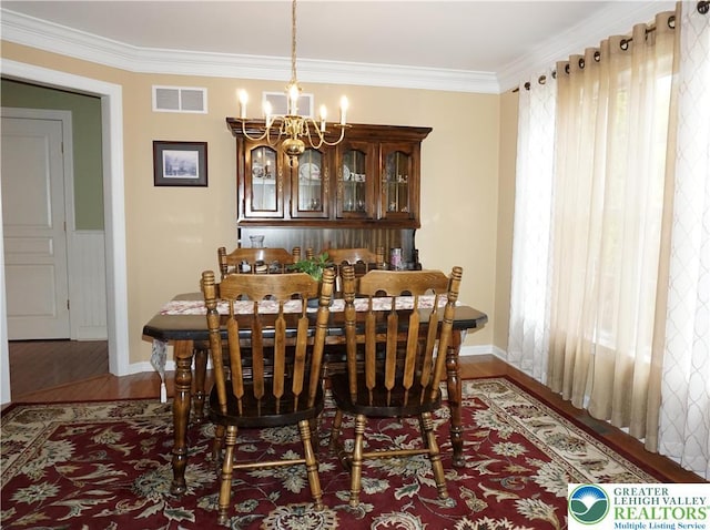 dining room with baseboards, a chandelier, wood finished floors, and crown molding