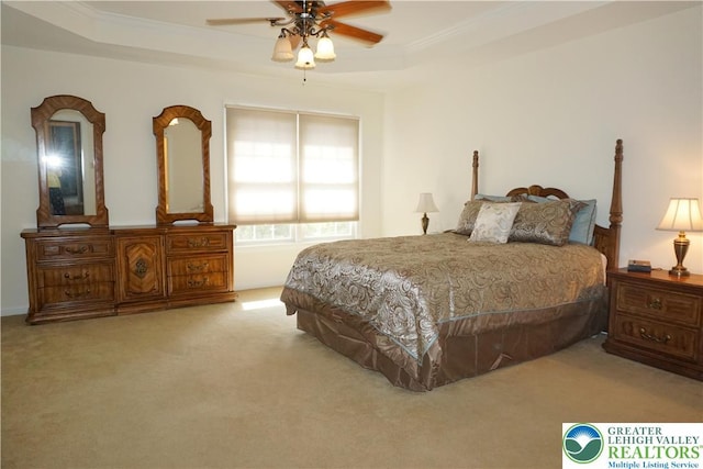 bedroom featuring carpet floors, a tray ceiling, crown molding, and ceiling fan