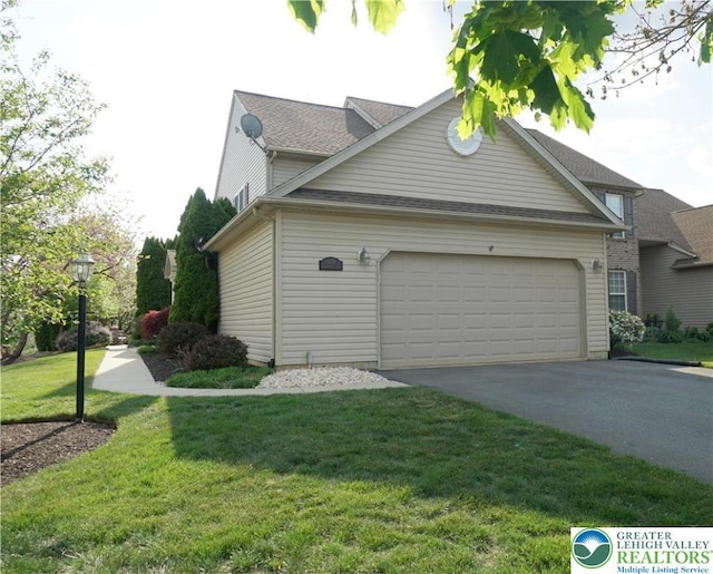 view of side of home featuring an attached garage, asphalt driveway, a yard, and roof with shingles