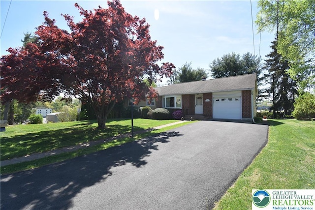 view of front of house with an attached garage, asphalt driveway, a front yard, and brick siding