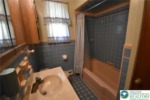 full bath with tile walls, a sink, shower / bath combo, a wainscoted wall, and a baseboard heating unit
