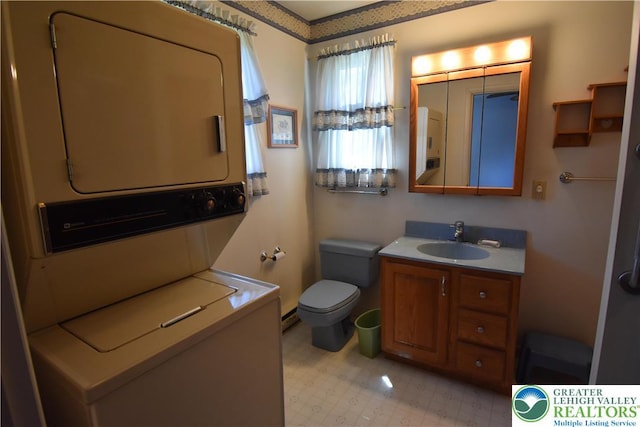 bathroom with stacked washer and clothes dryer, toilet, vanity, and tile patterned floors