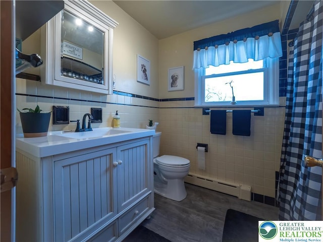 full bath with a baseboard radiator, tile walls, toilet, wood finished floors, and vanity
