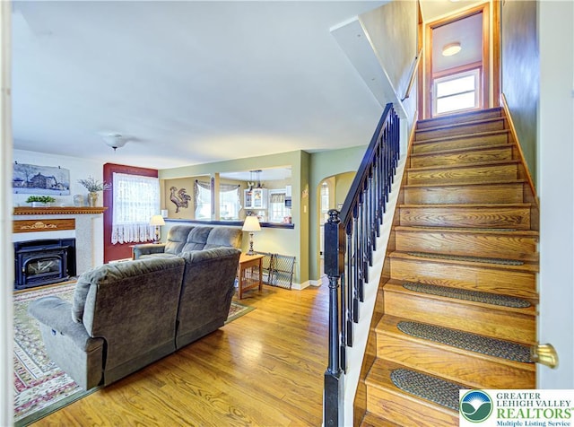 stairway featuring a fireplace, wood finished floors, and baseboards
