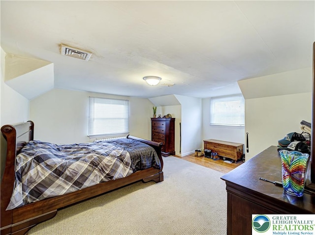 bedroom with multiple windows, vaulted ceiling, and light colored carpet
