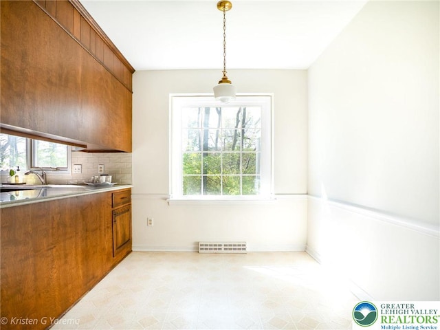 kitchen featuring brown cabinets, plenty of natural light, baseboards, and backsplash