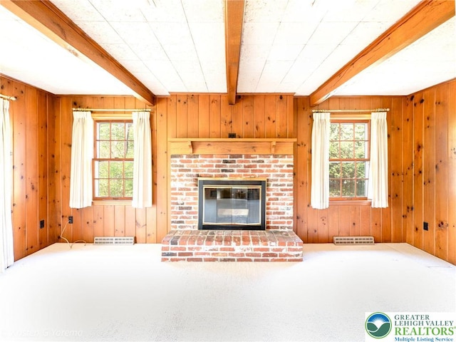 unfurnished living room featuring beam ceiling, carpet flooring, wood walls, and a fireplace