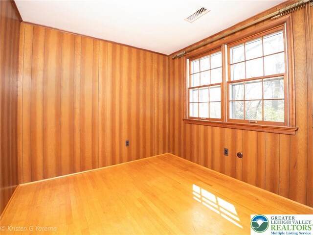 empty room featuring plenty of natural light, wood walls, and wood finished floors