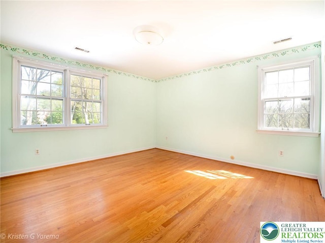 unfurnished room featuring plenty of natural light, light wood finished floors, and baseboards