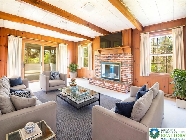 living area with beamed ceiling, wood walls, carpet, and a brick fireplace