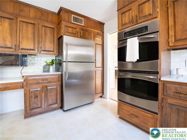 kitchen with stainless steel appliances, light countertops, decorative backsplash, and brown cabinets
