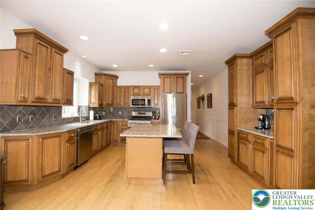 2690 Greens Dr, Lower Saucon Twp, PA 18055 - kitchen with appliances with stainless steel finishes, brown cabinetry, a sink, light wood-style flooring, and a center island
