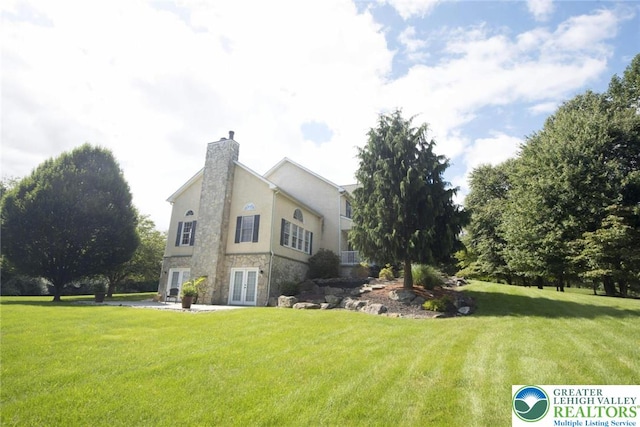 2690 Greens Dr, Lower Saucon Twp, PA 18055 - view of home's exterior with french doors, stone siding, a yard, a chimney, and stucco siding
