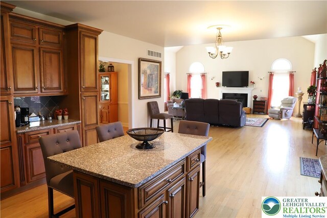2690 Greens Dr, Lower Saucon Twp, PA 18055 - kitchen featuring a kitchen breakfast bar, a chandelier, light wood-style floors, decorative backsplash, and vaulted ceiling