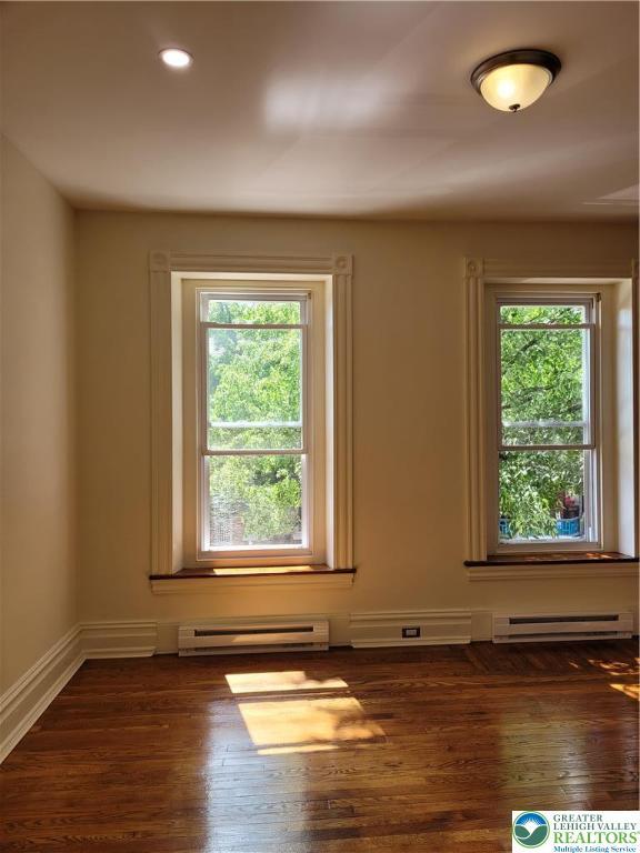 spare room with a baseboard heating unit, dark wood-type flooring, recessed lighting, and baseboards