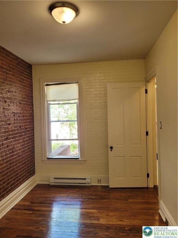 unfurnished room with a baseboard radiator, brick wall, dark wood-style flooring, and baseboards
