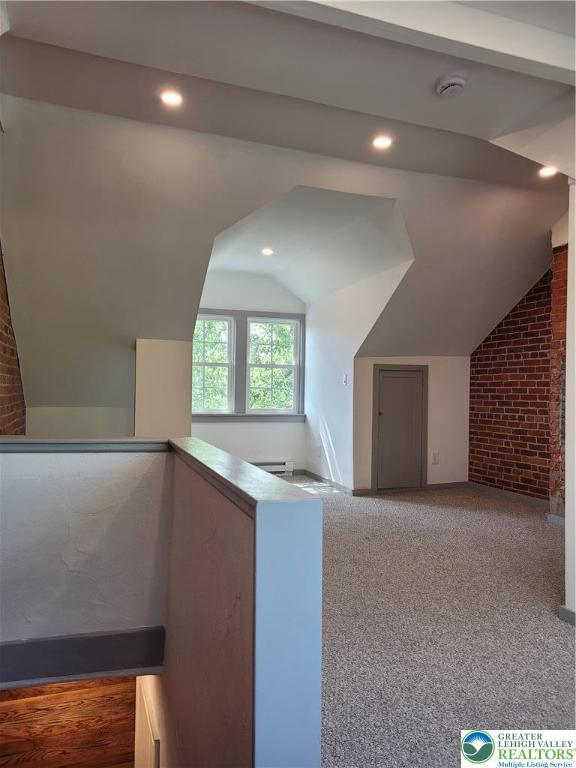 additional living space with brick wall, recessed lighting, vaulted ceiling, and carpet floors