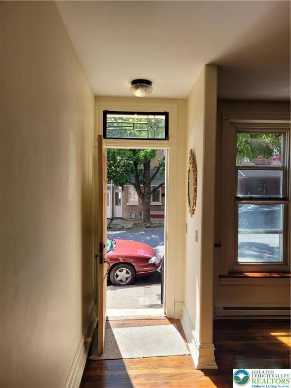 entryway with a baseboard heating unit, wood finished floors, and baseboards